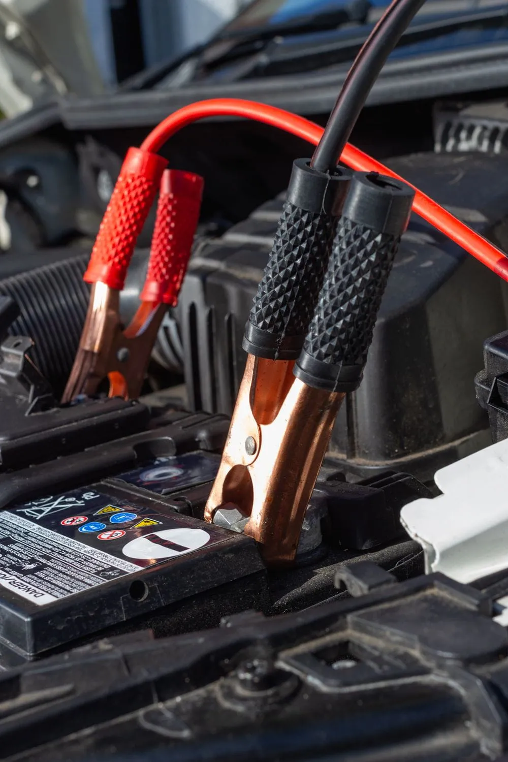 Jump start cables connected to a vehicle battery for roadside assistance